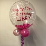 Personalised bubble with pink fluffy feathers inside . 5 inch latex balloons as a collar underneath . Pink vinyl lettering . Helium filled .